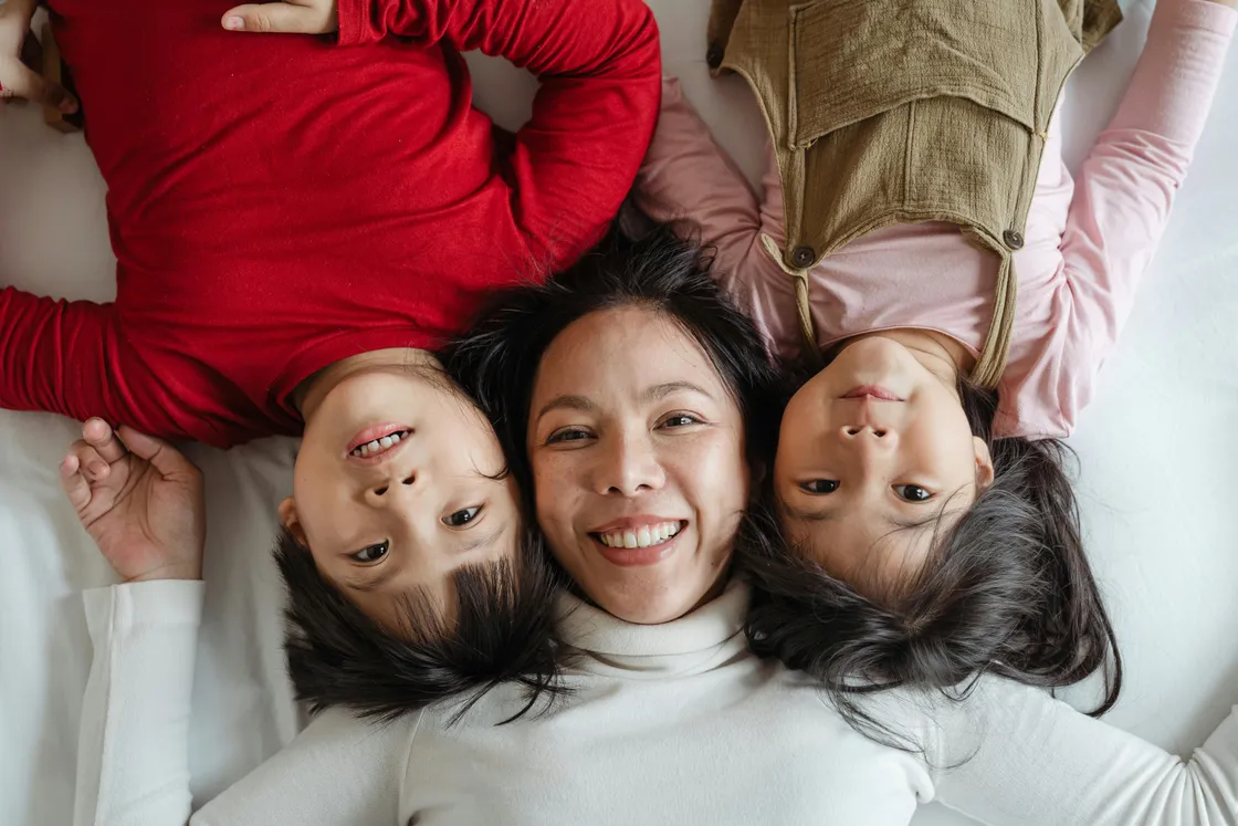 Florida mother and her two children resting and laughing together on a bed at home