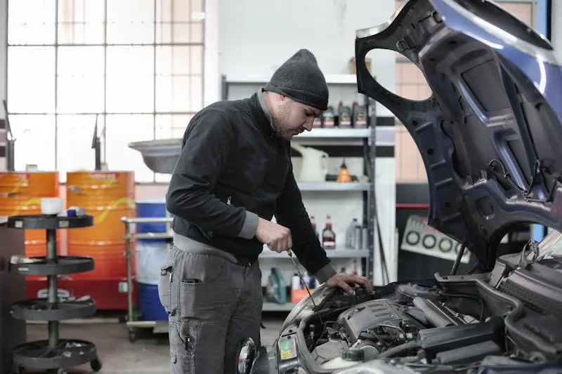 Mechanic leaning over an engine bay inspecting components in a small independent Florida shop