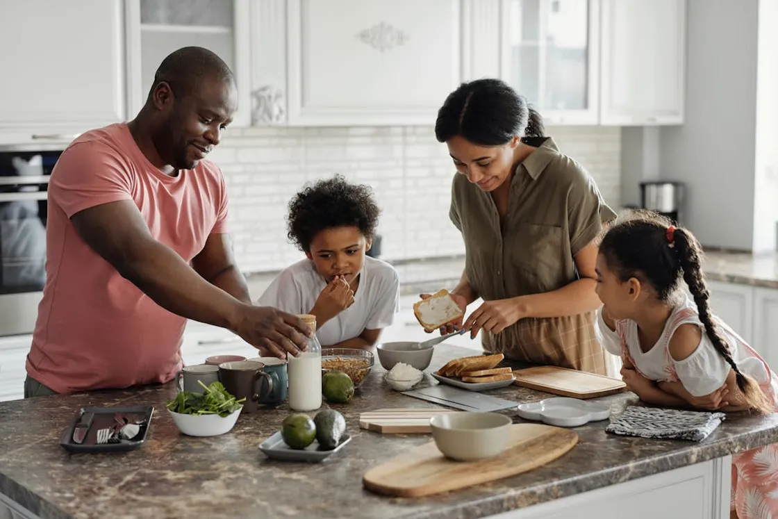 Florida family of three generations preparing a healthy breakfast together at a kitchen island, the kind of low-pressure morning setting where extended-family life insurance conversations work best